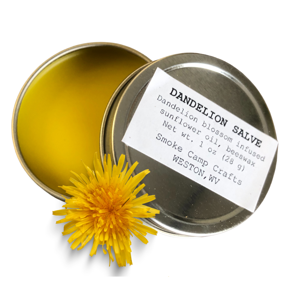 An open tin of Smoke Camp Crafts Dandelion Blossom Salve (1 oz) sits with its labeled lid and a fresh dandelion. Made with sunflower oil and beeswax, this herbal balm soothes dry skin and eczema for kids and adults.