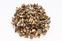 Smoke Camp Crafts Burdock Root, Dried, 1oz is displayed as a pile of small, irregular pieces arranged in a circle on a white surface.